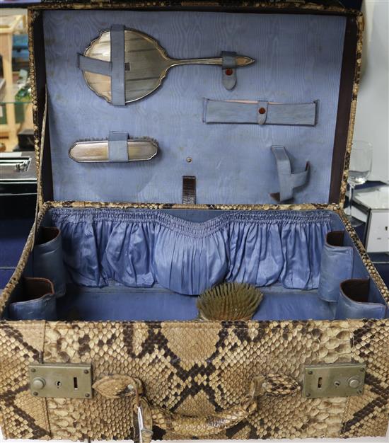 A 1930s python skin vanity case containing two silver mounted brushes, a mirror and a comb, case 51cm.